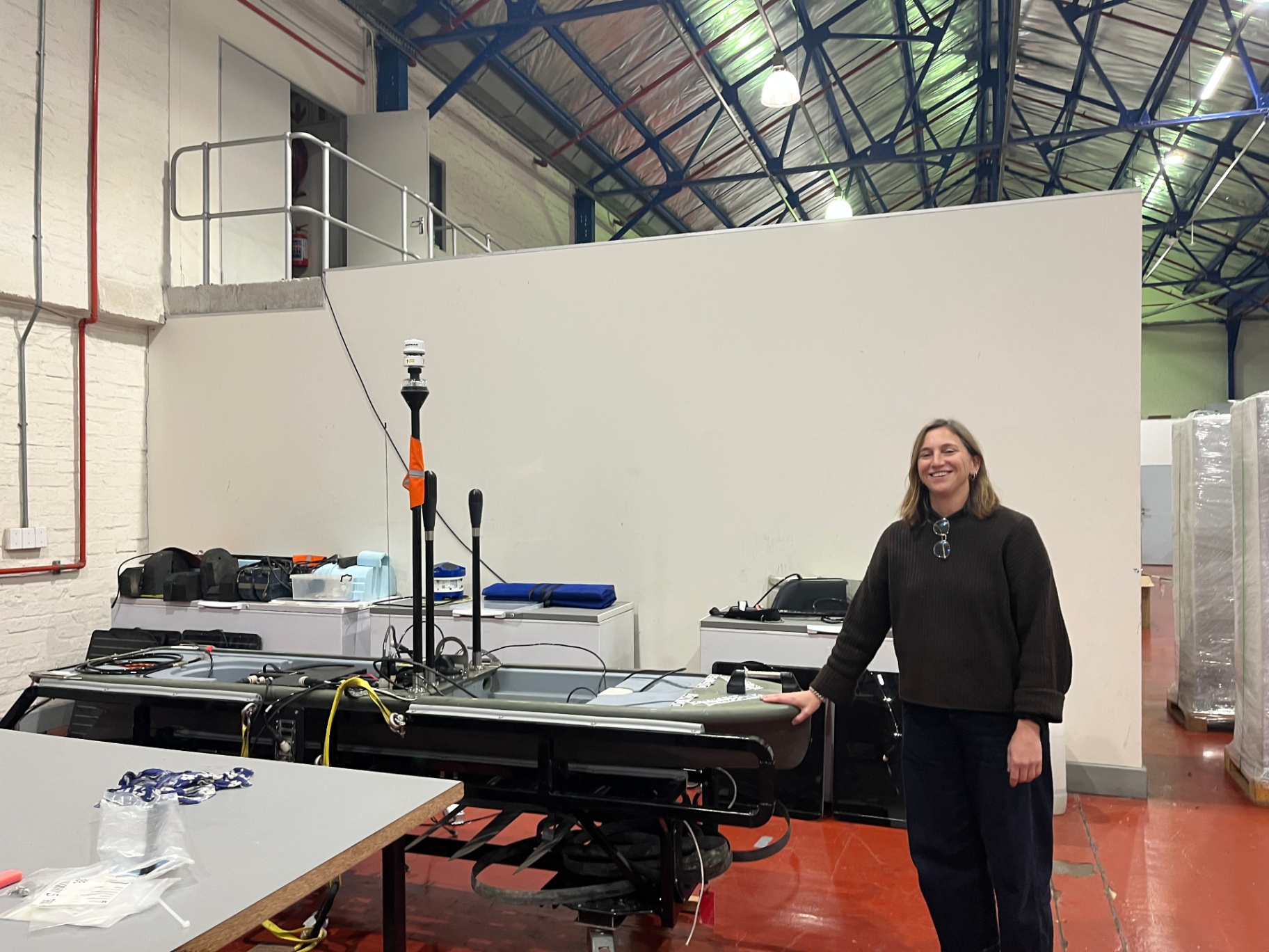 A researcher beside a large experimental apparatus in a workshop